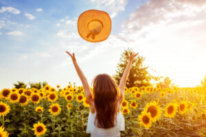 mujer-joven-que-camina-campo-floreciente-girasol-que-lanza-sombrero-arriba-que-divierte-vacaciones-verano_106029-370